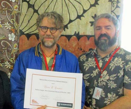 Chris O'Connor holds his award certificate and stands next to Neil   